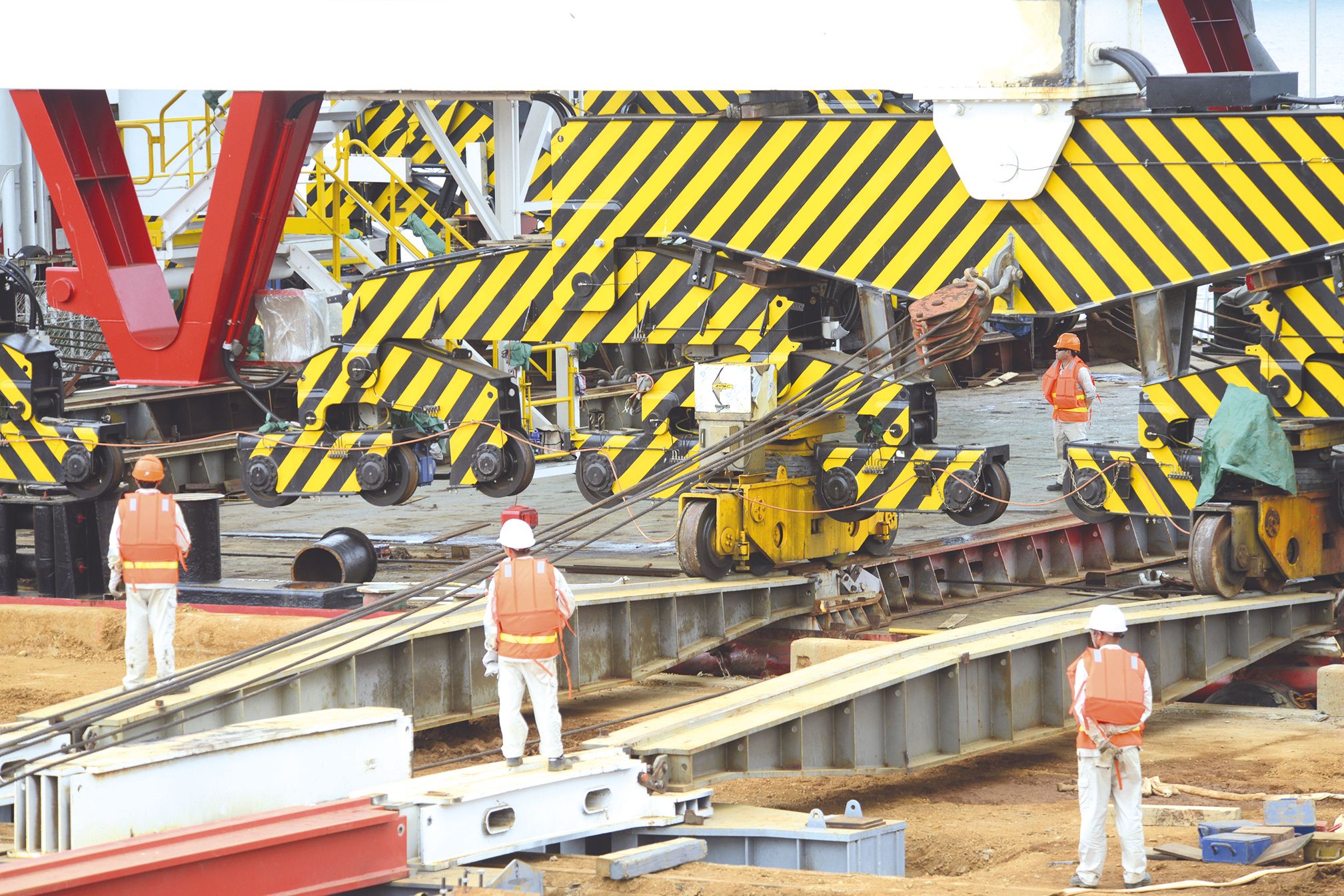 Tirée par des câbles sous la supervision de travailleurs spécialisés venus de Chine, la grue avance petit à petit le long de rails temporaires. Un morceau du convoyeur a dû être découpé pour permettre à l’engin d’être installé.