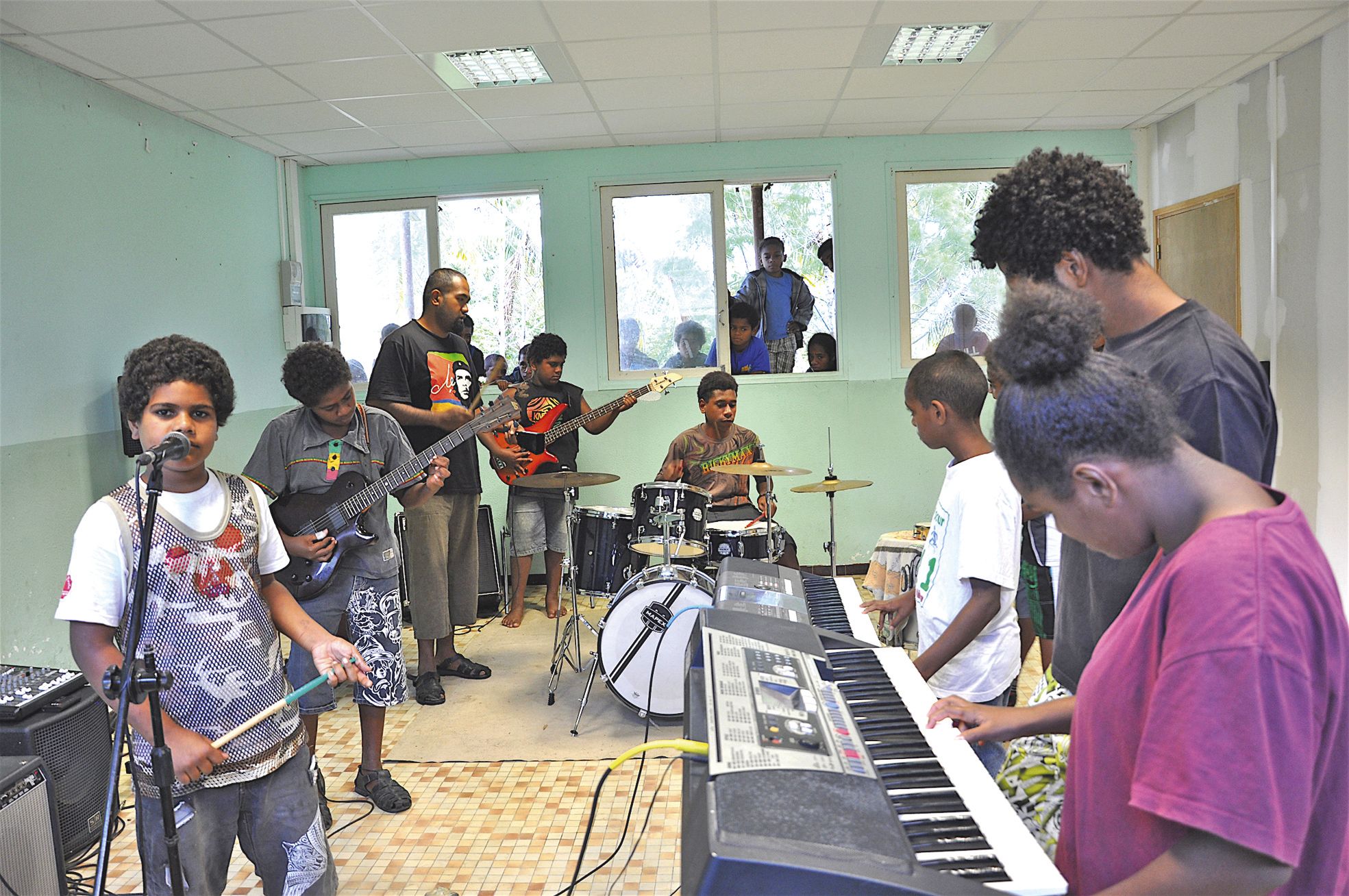 Un groupe d'enfants, encadrés par Djeimmy Pebou-Hamène et Étienne Poygnena, s'initie à la pratique instrumentale collective.